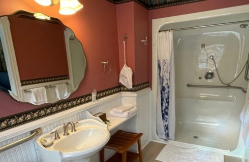 A bathroom with pedestal sink, decorative mirror and large stand up shower